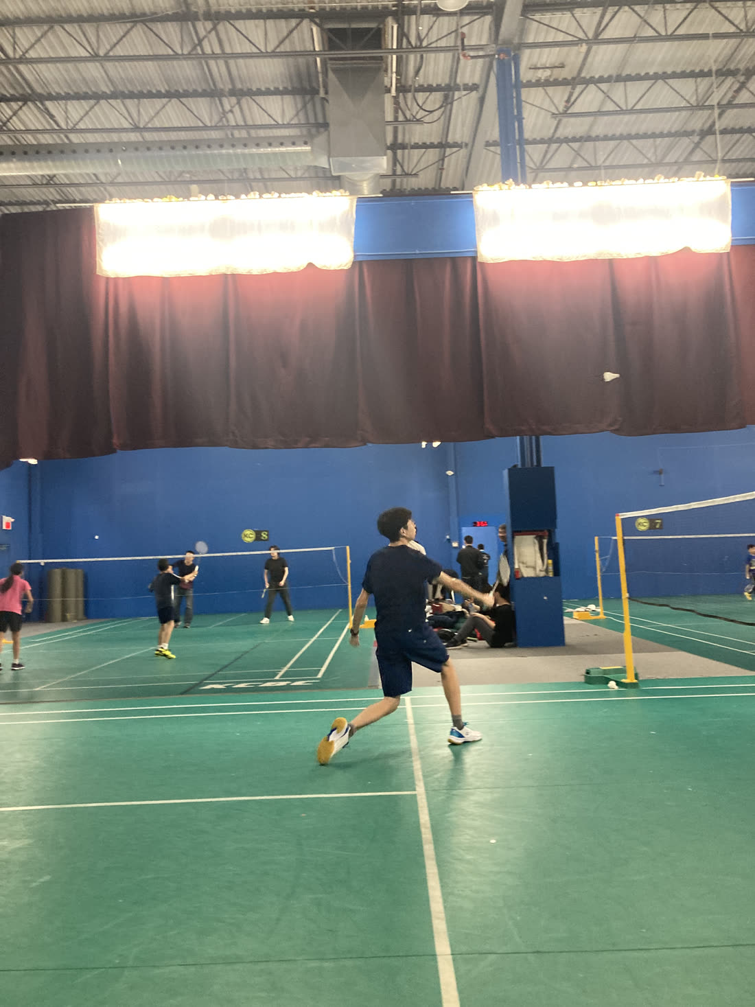 Playing badminton at the club, mid-stroke.